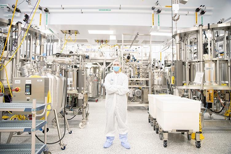 Man wearing white protective suit standing in the middle of laboratory space