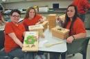 three women in classroom showing their woodworking projects